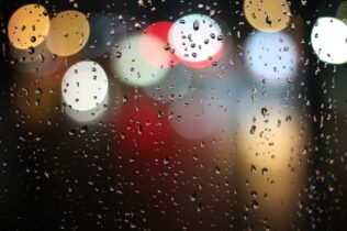 Blurred lights through a rain-splattered window
