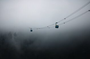 Two cable cars suspended in fog