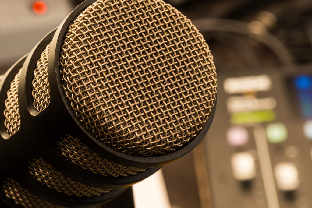 Close-up view of a microphone in a studio, with a mixing board in the background