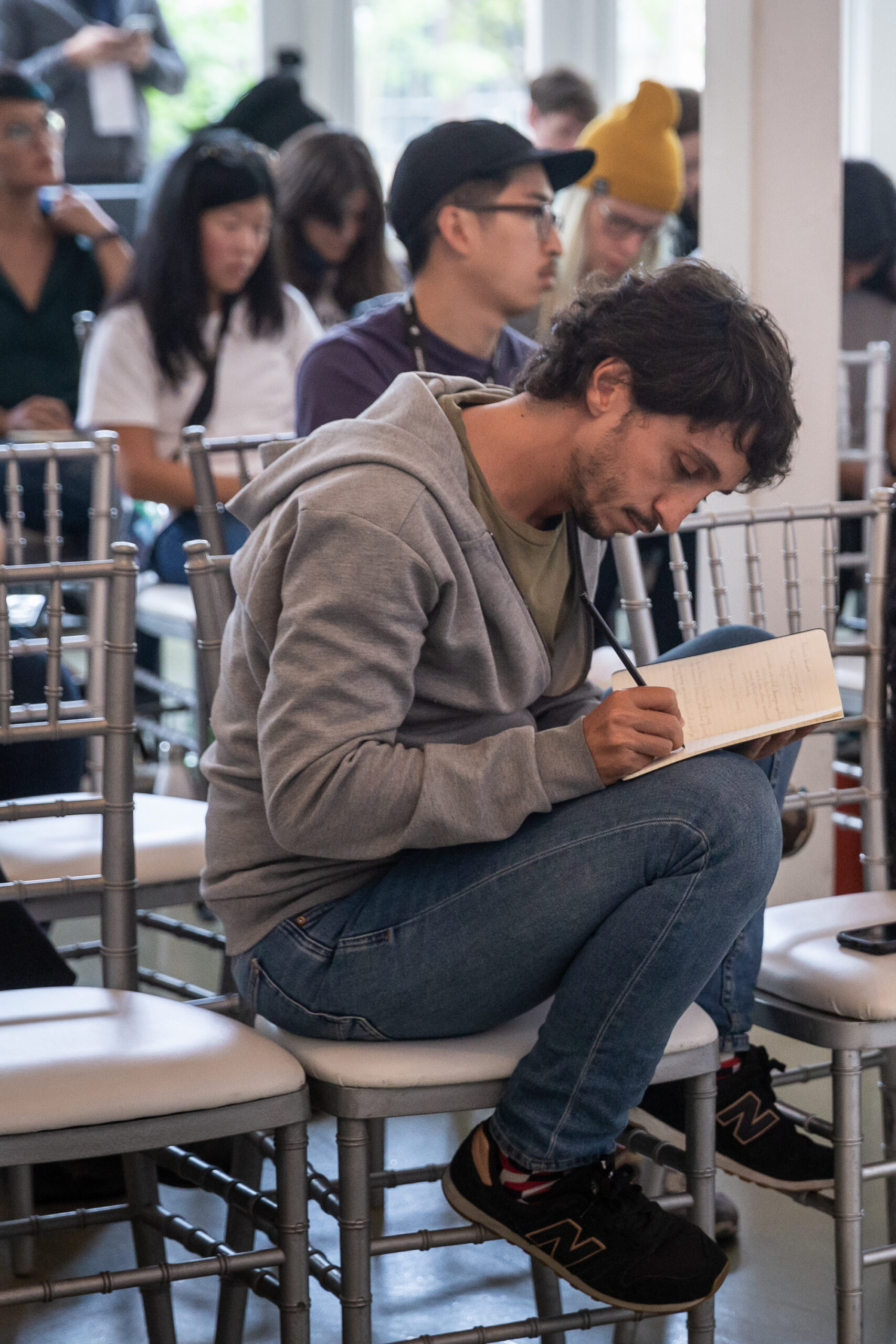 Tight shot of a participant taking detailed notes in a notebook, with several others doing the same in the background